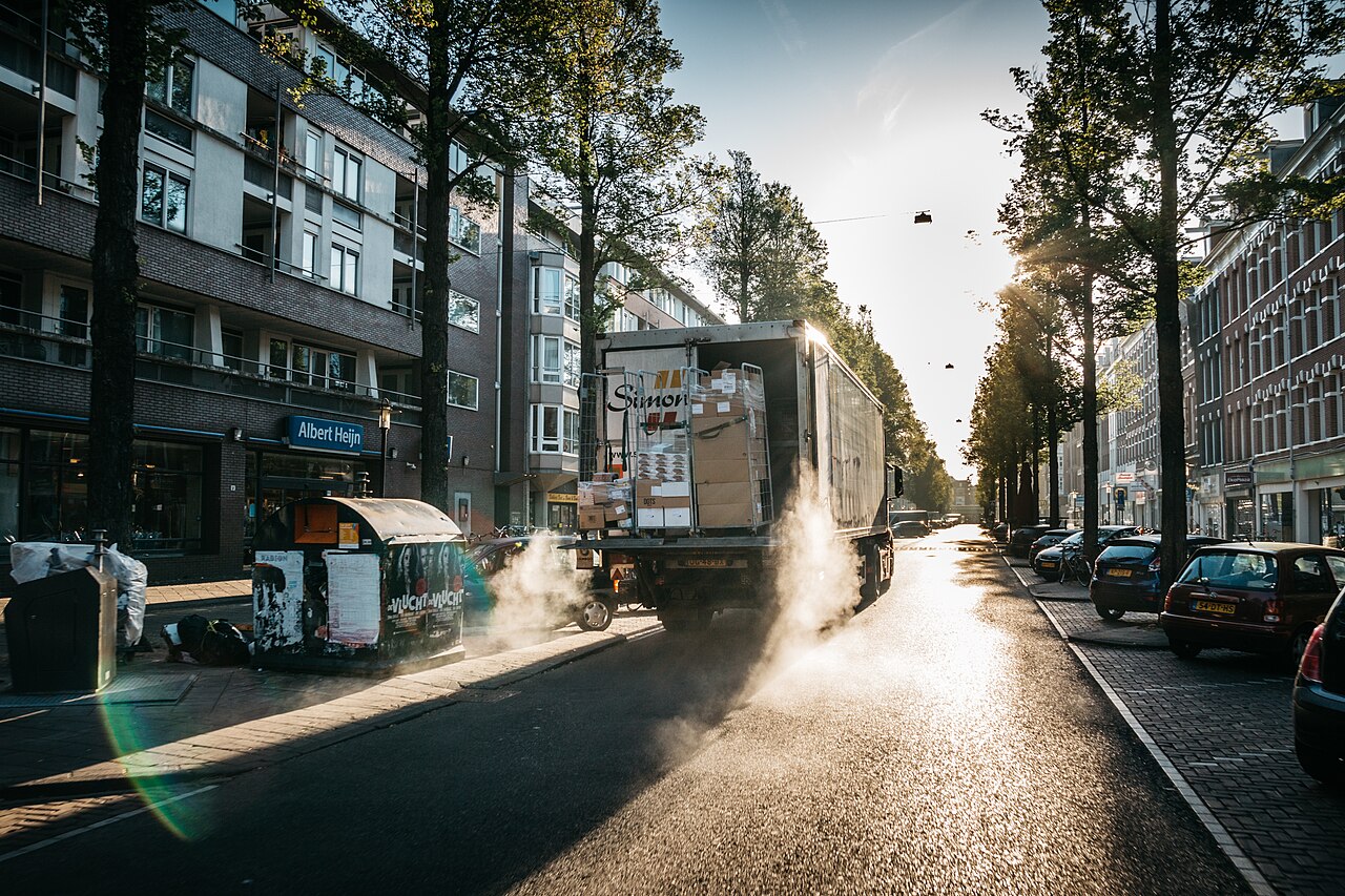 A delivery truck parked on an urban street at sunrise with boxes loaded in the back.